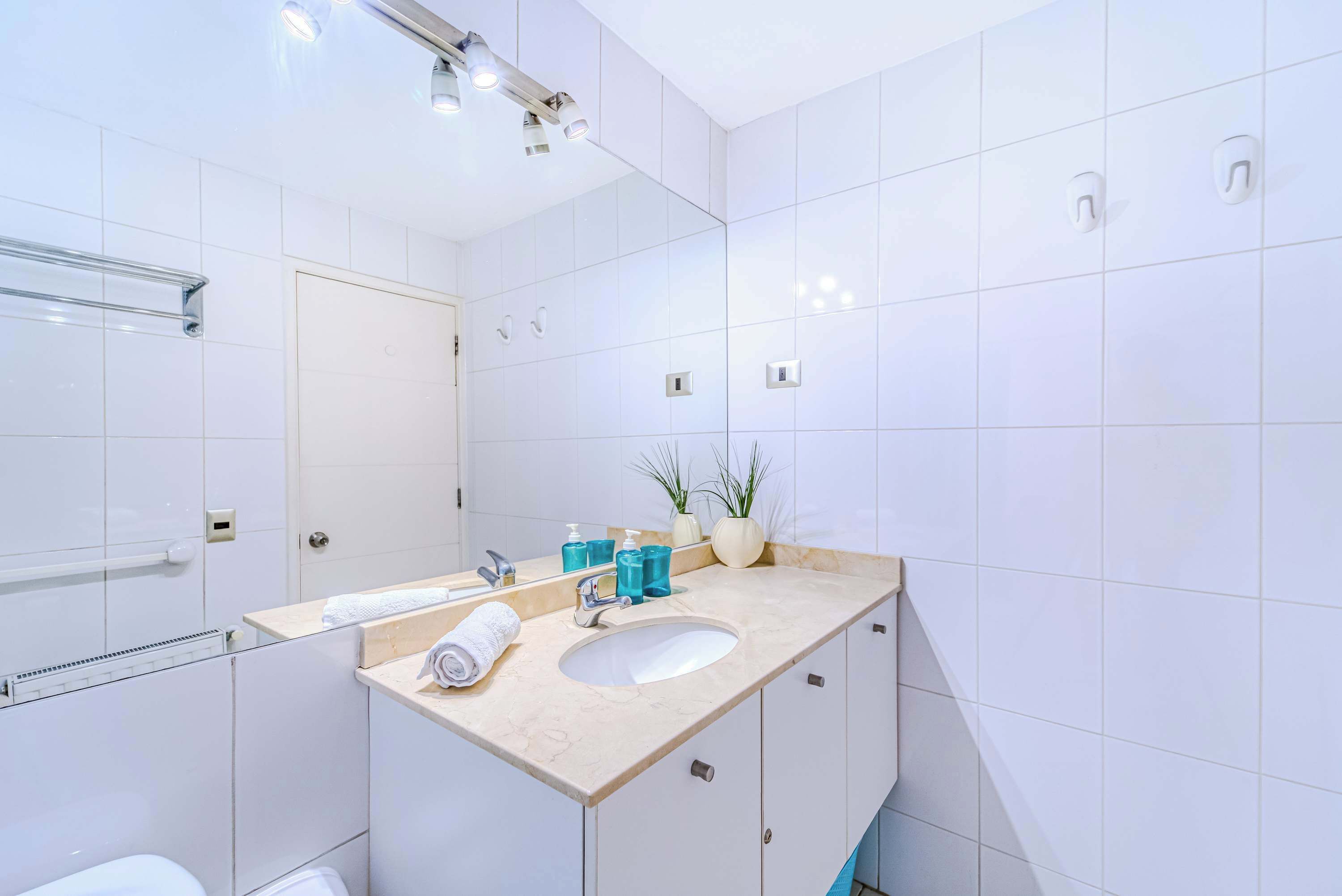 A modern bathroom with a large mirror, a sink, and a toilet.