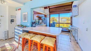 Una cocina con una isla grande, taburetes de bar y vistas al exterior.