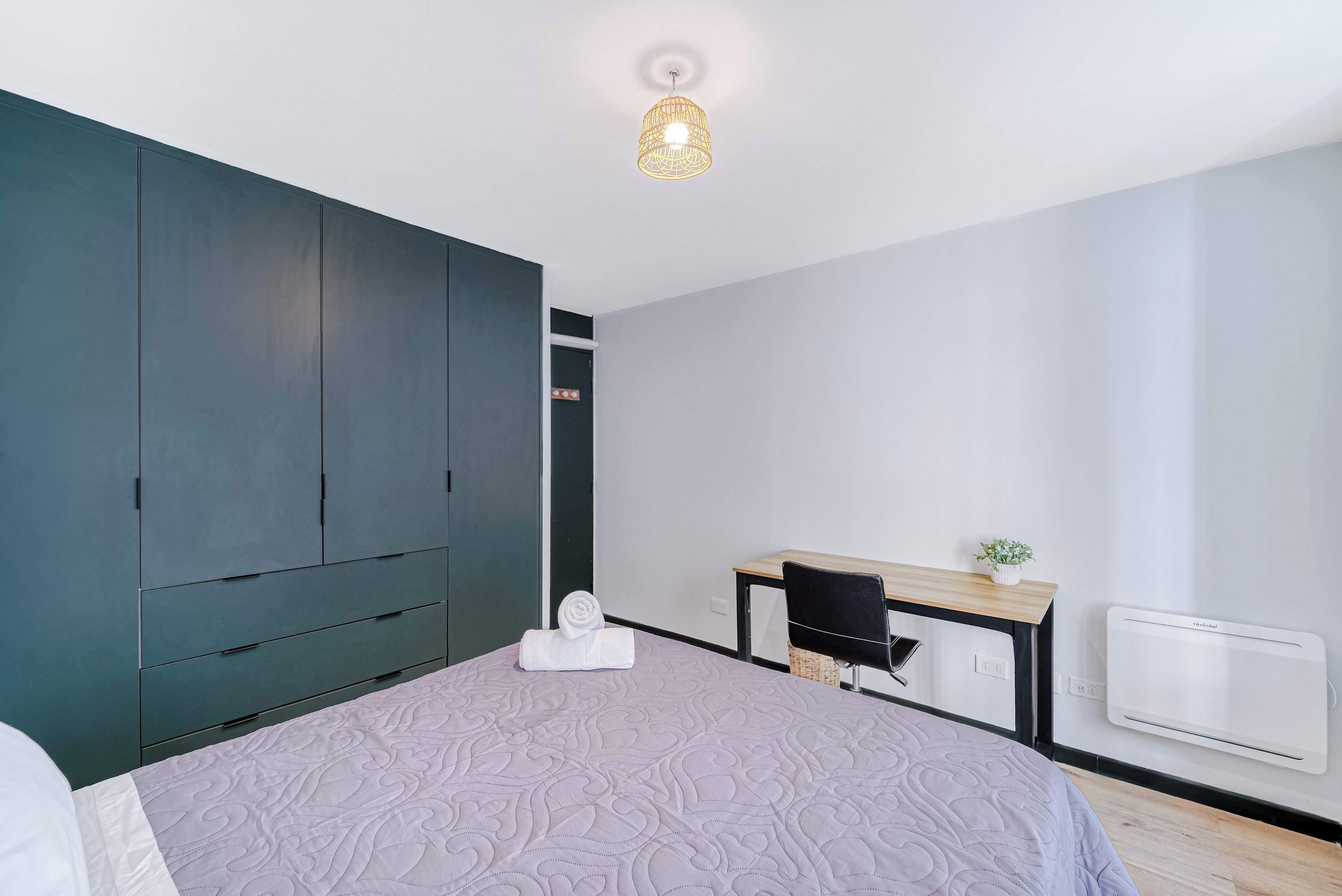 Quarto moderno com cama, escrivaninha, cadeira e guarda-roupa.