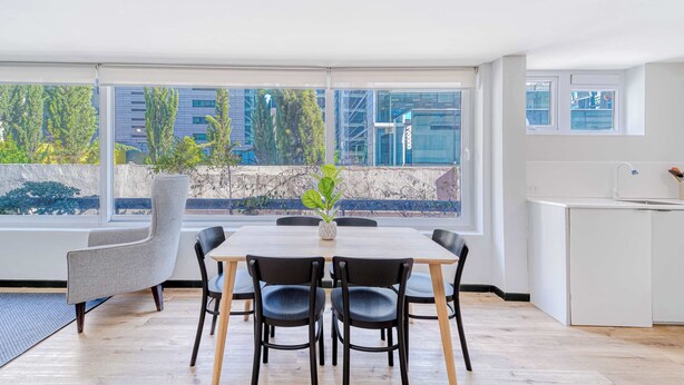 Una cocina moderna con un amplio ventanal, un comedor con mesa y sillas, y una planta en maceta.