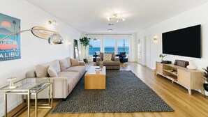 En moderne stue med sofa, sofabord, tv og et stort vindue med udsigt.