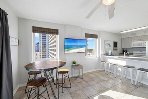 A modern kitchen with a large island, bar stools, and a dining table with stools. - Royal Palms 1208 by Liquid Life (Gulf Shores)