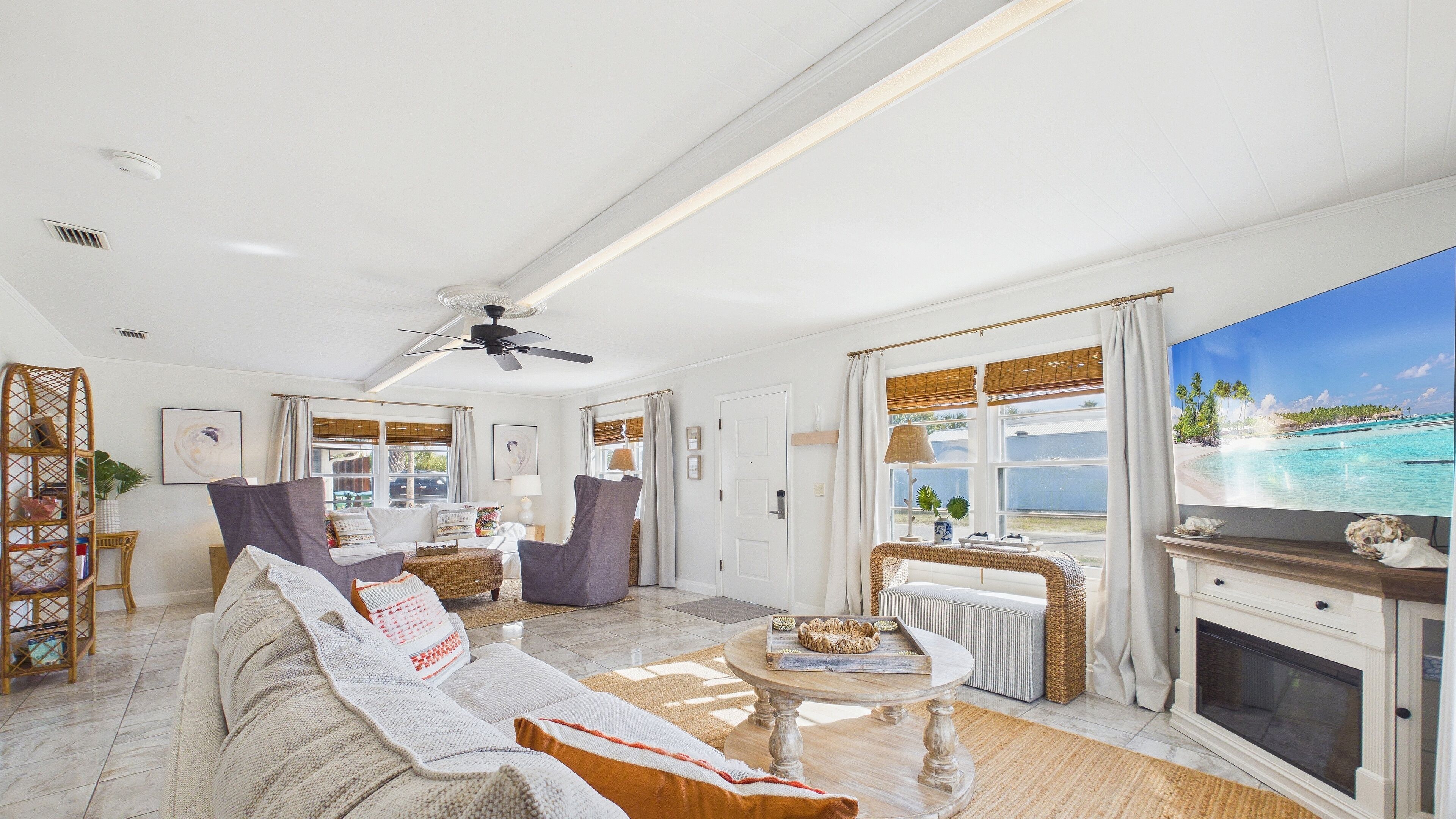 Ein geräumiges Wohnzimmer mit großem Fenster, Deckenventilator und Kamin.