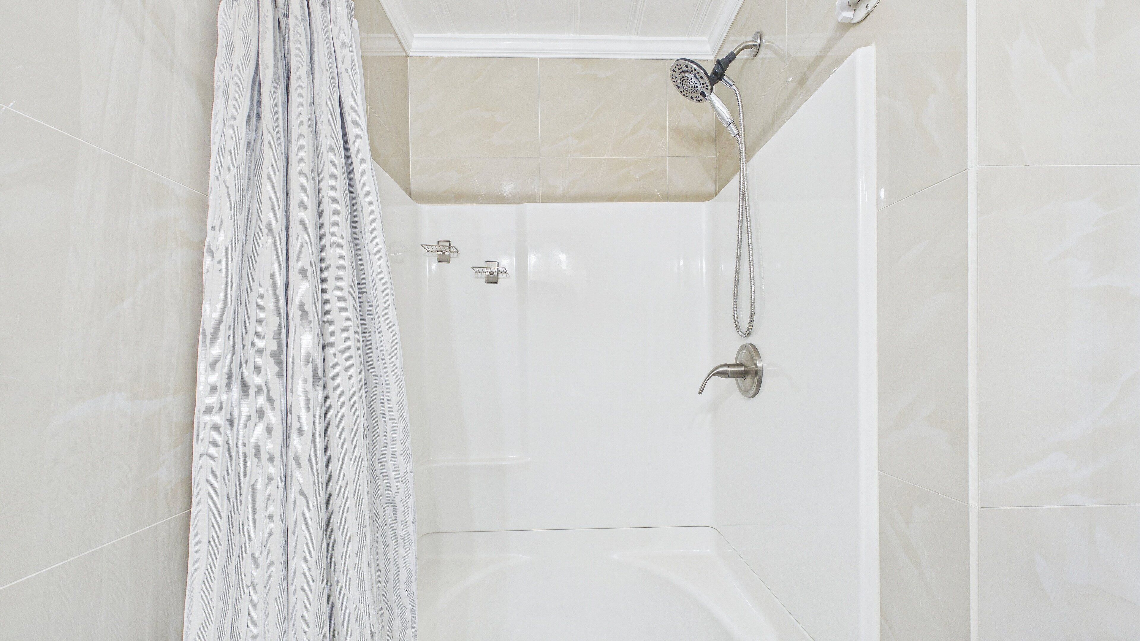 Une salle de bain moderne équipée d’une douche, d’un porte-serviettes et de toilettes.