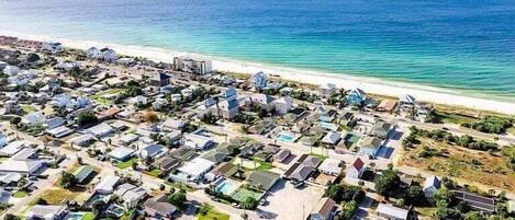 An aerial view of a coastal residential area with houses, roads, and a beach.