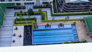 Vista aérea de um edifício moderno com piscina no terraço, terraços ajardinados e área de estacionamento.