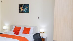 Una camera d'albergo con un letto, due abat-jour, una scrivania, una sedia e un quadro appeso al muro.