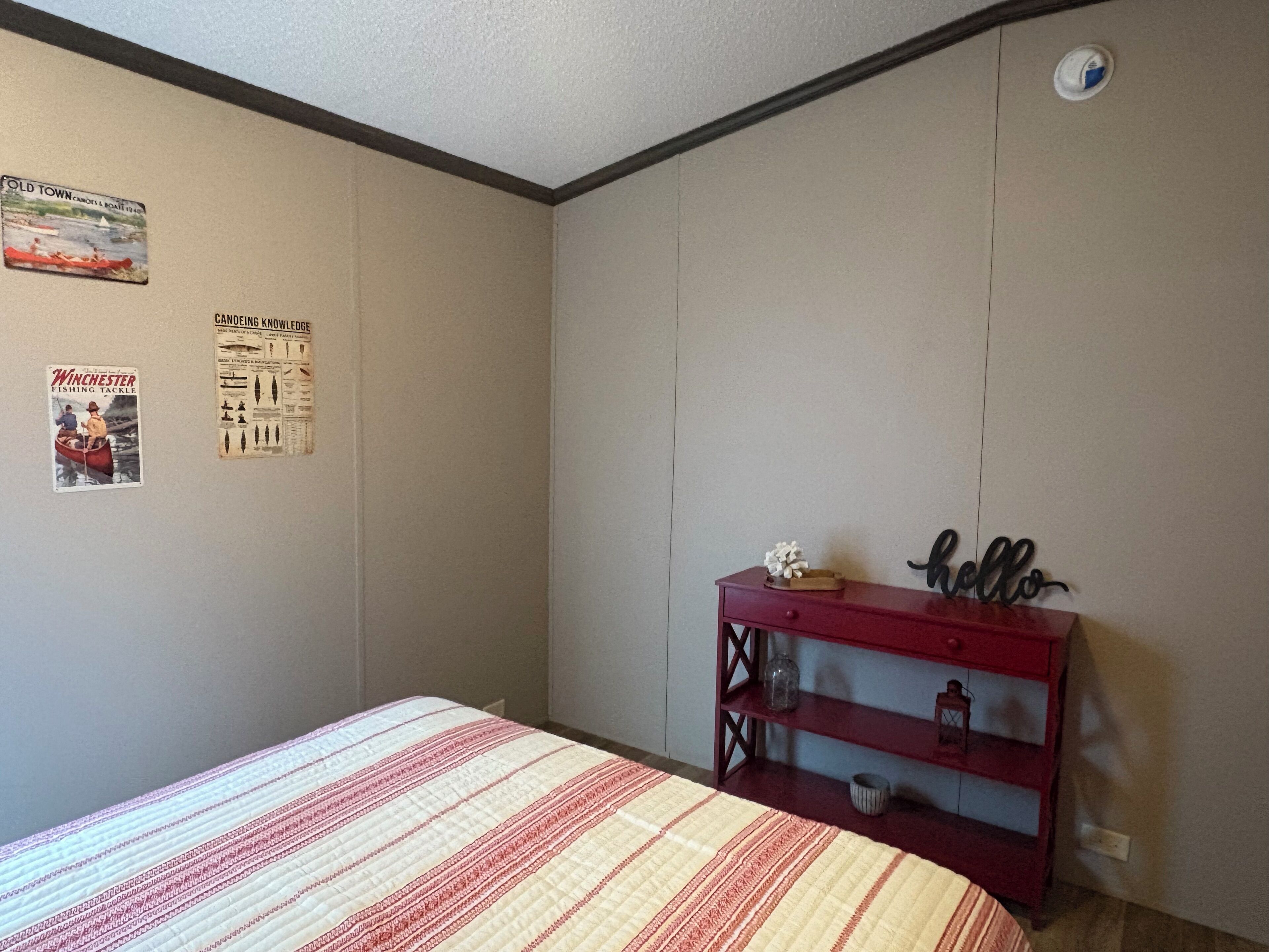 Ein Schlafzimmer mit Bett, Schminktisch und Wanddekorationen, darunter Poster.