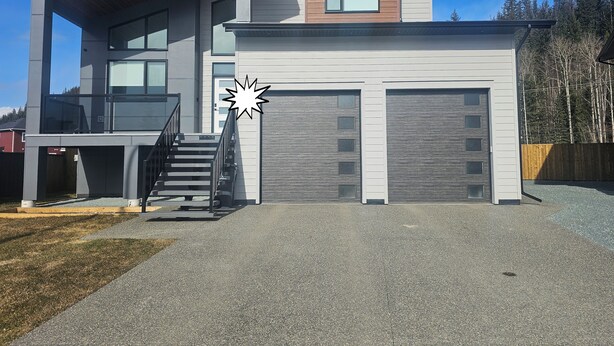 Ein modernes, zweistöckiges Haus mit überdachter Veranda, einer Treppe und einer Garage.