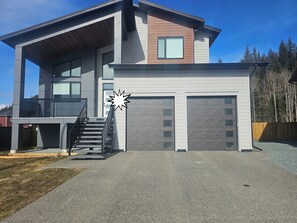 Et moderne hus med to etager, en overdækket veranda, trappe og garage.