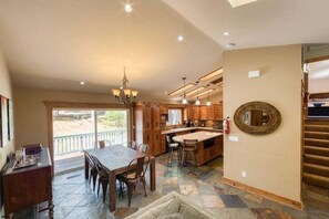 A spacious kitchen with a large island, wooden cabinets, and a dining area with a table and chairs.