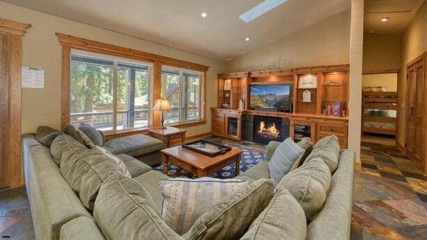 Una sala de estar acogedora con chimenea, ventanas grandes y televisor.