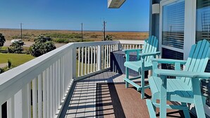 Een balkon met uitzicht op het strand, een tafel en twee stoelen.