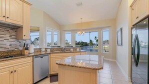 A modern kitchen with granite countertops, wooden cabinets, and a central island. - Rose Lake Escape - Gulf Access & Pet Friendly (Cape Coral)