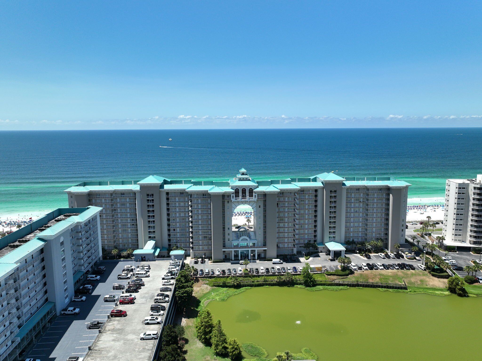 A large hotel with multiple floors, a central courtyard, and a view of the ocean.