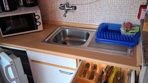 A kitchen with a sink, a microwave, and a drawer organizer with utensils.