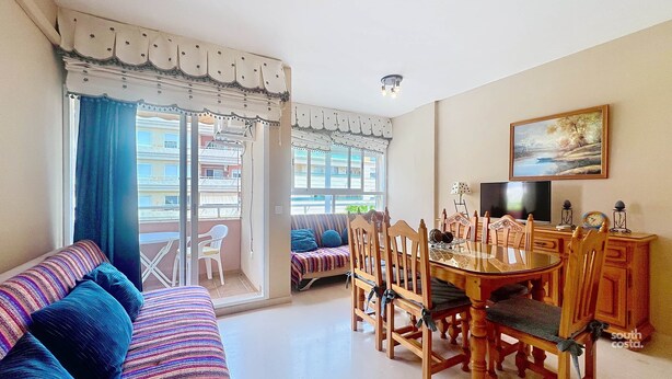 Una sala de estar con sofá, mesa de comedor, sillas y televisor.