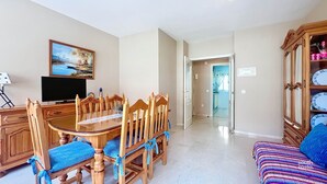 Un comedor con una mesa y sillas de madera, televisión y un cuadro en la pared.