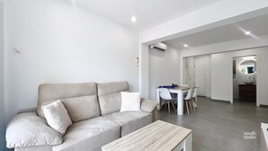 A modern living room with a beige sofa, a coffee table, and a dining area with a white table and chairs. - Modern Central Apartment - South Costa, Nerja (Nerja)