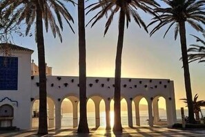 A building with a series of arches and palm trees in front. - Torresol Sea View (Nerja)