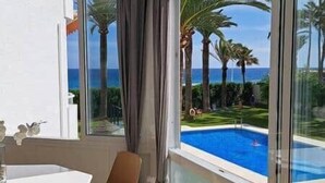 Una habitación con vista a una piscina, palmeras y el océano.
