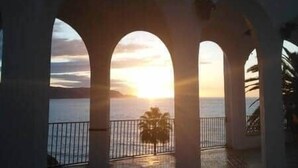 Un balcón con arcos que da a una masa de agua al atardecer.
