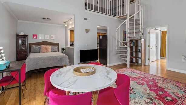 Ein geräumiges Schlafzimmer mit einem großen Bett, einem runden Esstisch und einer Wendeltreppe, die zu einer oberen Ebene führt.
