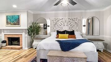 Un dormitorio con una cama grande, chimenea y ventilador de techo.