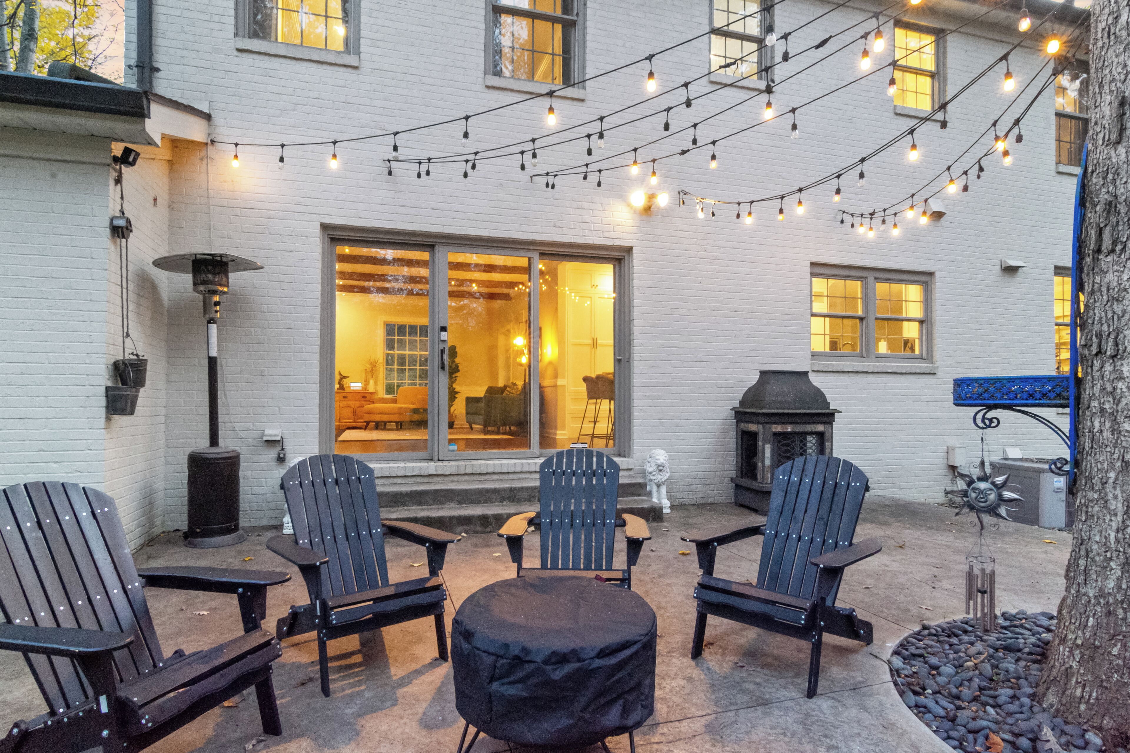 Eine Terrasse mit Adirondack-Stühlen, einem überdachten Tisch und Lichterketten.
