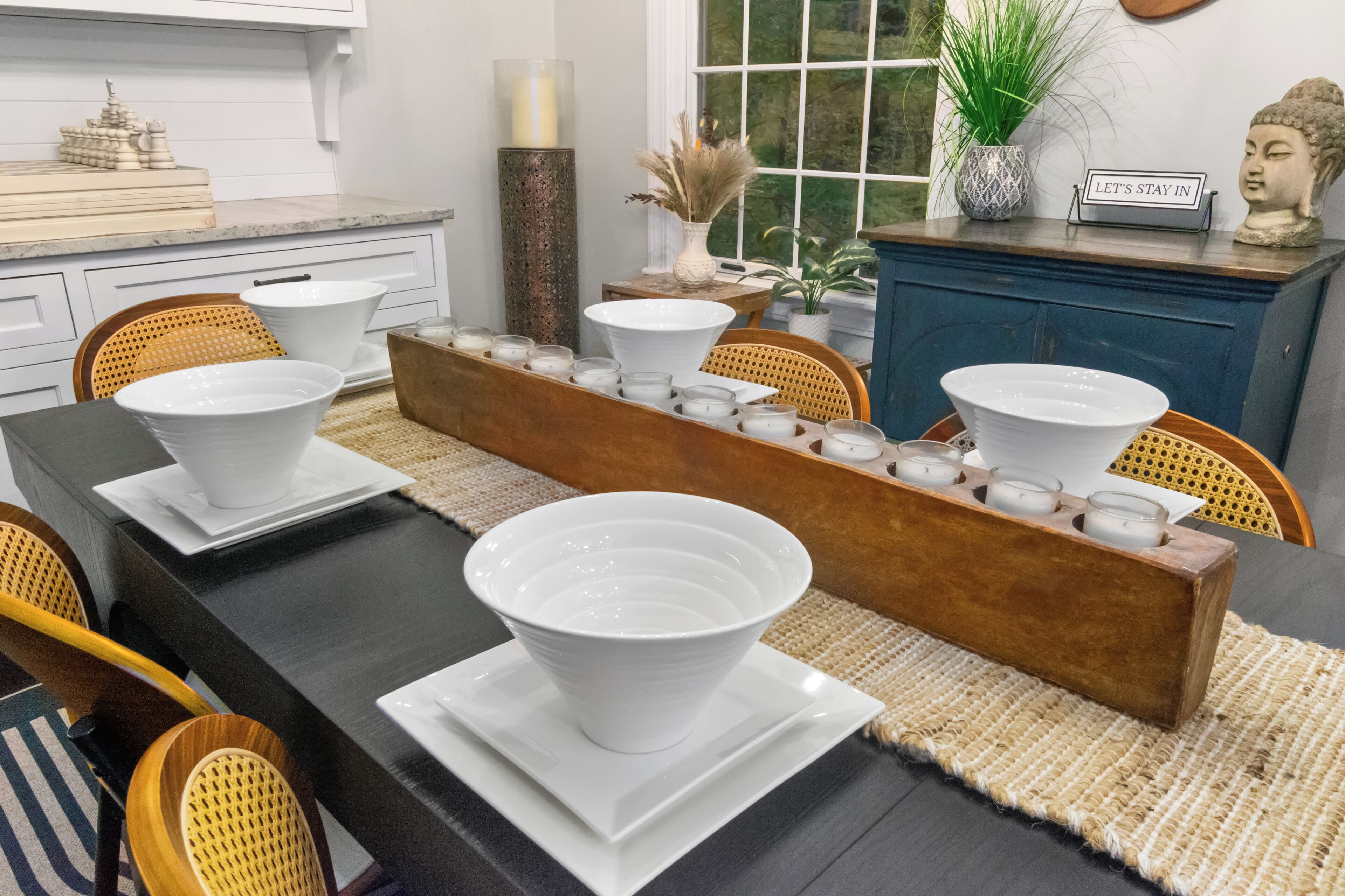 Un comedor con una larga mesa de madera, platos blancos y velas.