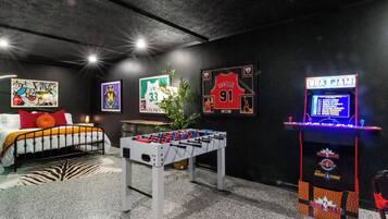 Een kamer met een tafelvoetbaltafel, een bed met een zebraprint vloerkleed en sportmemorabilia aan de muren.