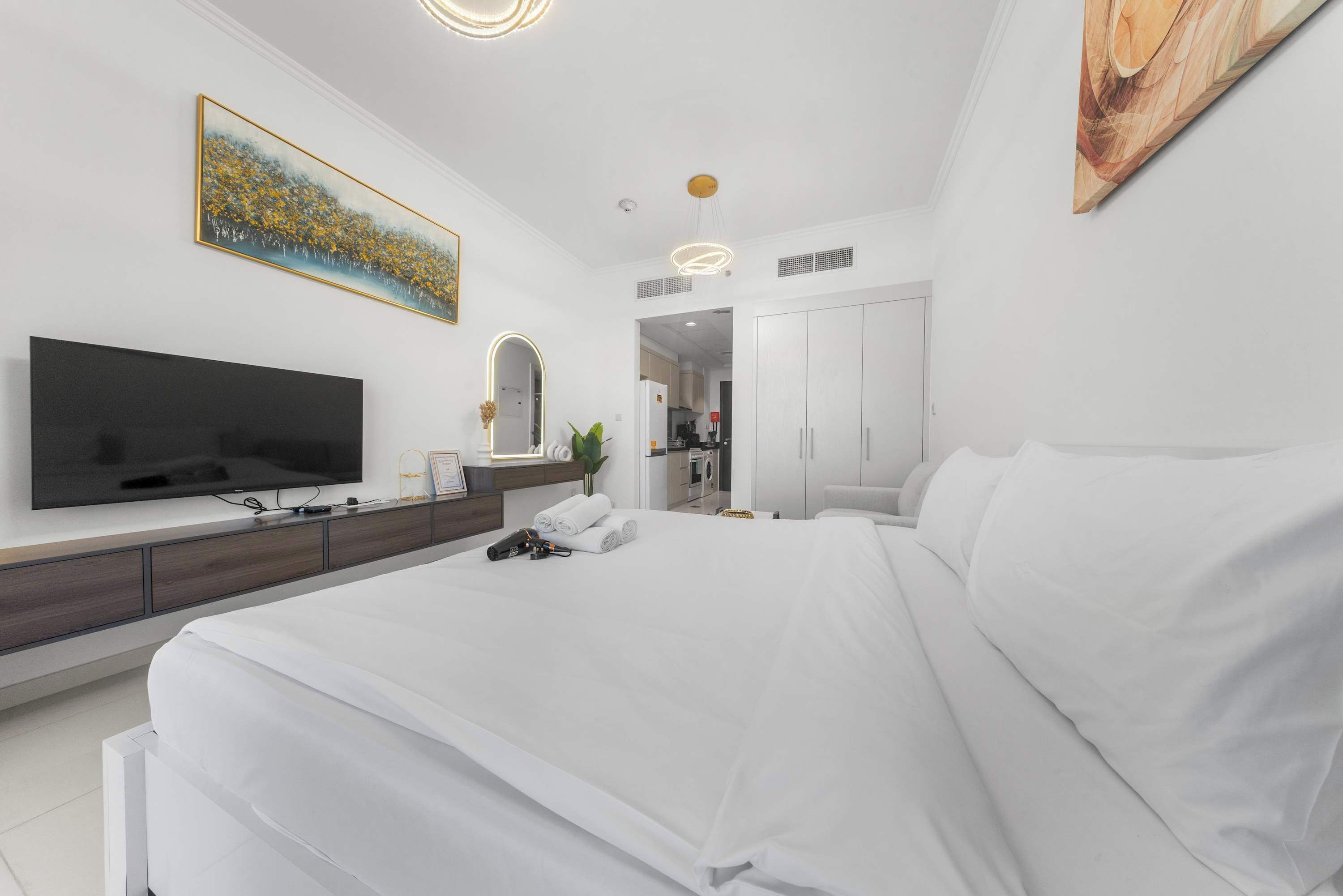 A modern bedroom with a large bed, a flat-screen TV, a bedside table, and a wardrobe.