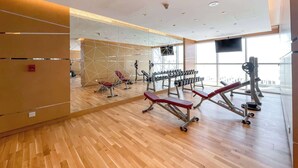 Un gimnasio moderno con suelos de madera, equipamiento de ejercicio y amplias ventanas.