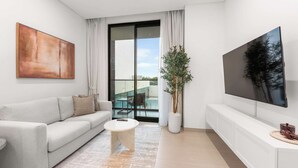 Un salon moderne avec un canapé, une table basse, un téléviseur et un balcon doté d’une porte vitrée.