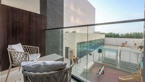 Un balcon avec des fauteuils en osier, une table et une vue sur une piscine et un toboggan.