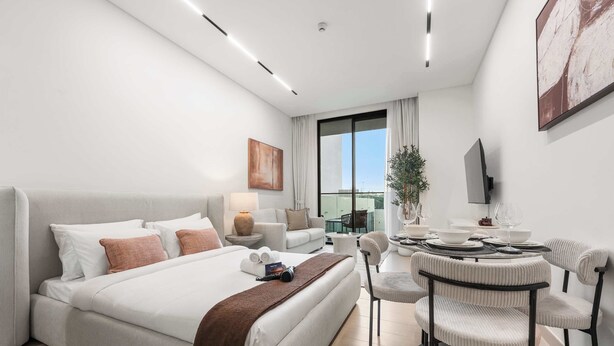 Une chambre d’hôtel moderne dotée d’un grand lit, d’un coin repas et d’une télévision.