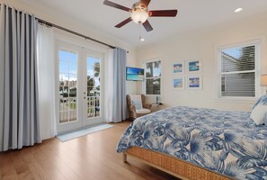 Ein Schlafzimmer mit Bett, Deckenventilator, Fernseher und Blick ins Freie.