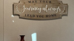 Un letrero de madera con el texto: 'Que tu viaje siempre te lleve de vuelta a casa'.