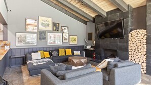 A modern living room with grey sofas, a wooden coffee table, and a fireplace with stacked logs. - Cozy Mtn Retreat w/Fireplace | Mins to Village (Mammoth Lakes)