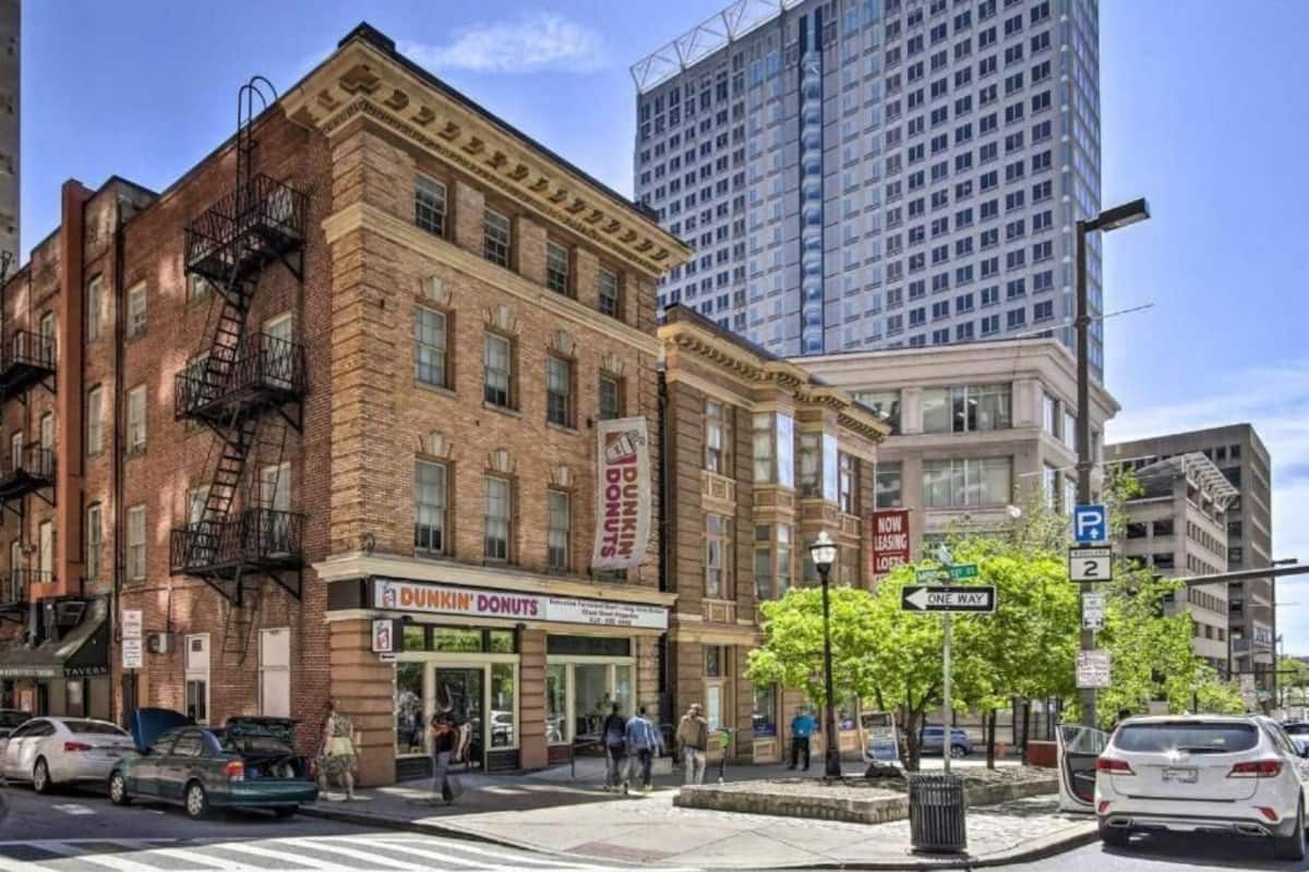 A street view with a Dunkin' Donuts on the corner, a parking sign, and a one-way street sign.