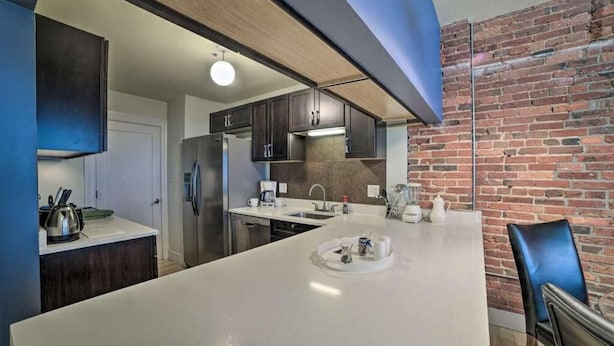 Una cocina moderna con una isla grande, armarios oscuros y una pared de ladrillo.