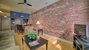 Una sala de estar con pared de ladrillo, ventilador de techo, chimenea y televisor.