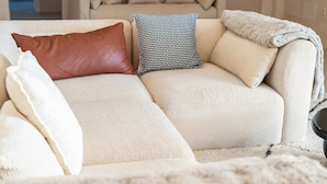 A beige sofa with multiple pillows, a blanket, and a patterned pillow. - Casa Angeles, Frontline Beach House (Torreguadiaro)