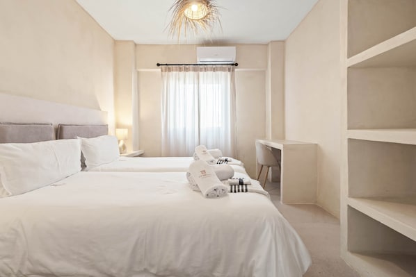 Ein Hotelzimmer mit zwei Betten, einem Schreibtisch, einem Stuhl, einem Kleiderschrank und einer Deckenleuchte.