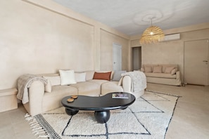 Ein Wohnzimmer mit einer Couch, einem Couchtisch, einer Hängeleuchte und einer Tür.