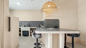 A modern kitchen with a marble countertop, black bar stools, and a woven light fixture. - Casa Angeles, Frontline Beach House (Torreguadiaro)