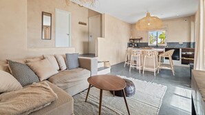 Ein modernes Wohnzimmer mit einer Couch, einem Couchtisch und einer Küchenzeile mit Esstisch.
