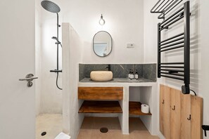 Un bagno moderno con doccia separata, uno specchio rotondo, un mobile vanitario in legno e un portascope.