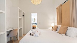A hotel room with a bed, a desk, a chair, a wardrobe, and a bathroom visible through an open door. - Casa Rosa, Frontline Beach House (Torreguadiaro)