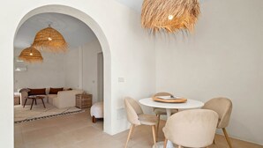A modern interior with a round dining table, beige chairs, and a large woven ceiling light. - Casa Rosa, Frontline Beach House (Torreguadiaro)